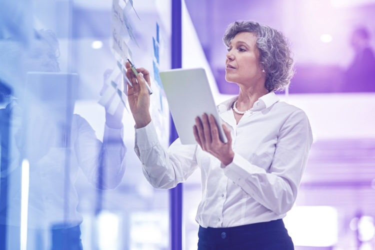 Cropped shot of a mature businesswoman writing notes on a glass wall in a modern office